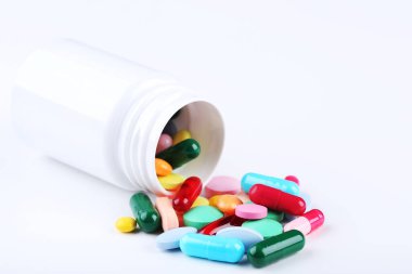 Beyaz arka planda renkli haplar ve şişe