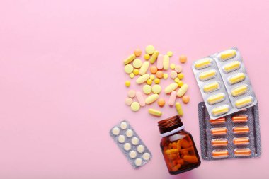 Pembe arka planda ilaç hapları ve şişe