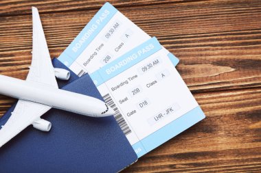 Biletli pasaportlar ve kahverengi ahşap arka planda uçak modeli.