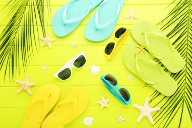 Terlikli yıldız balıkları, güneş gözlükleri ve yeşil ahşap masada palmiye yaprakları.