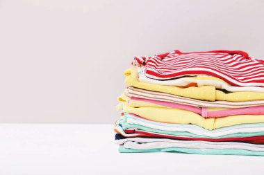 Gri arka planda farklı katlanmış bebek kıyafetleri.