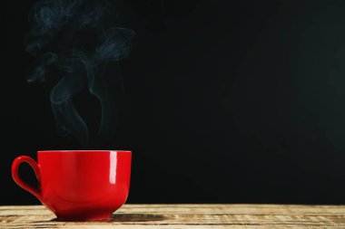 Siyah arka planda buharlı bir bardak içki.