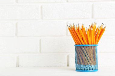 Sarı kalemler mavi sepette beyaz tuğla duvar zemininde