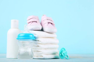 Şişeli bebek bezleri, emzik ve mavi arka planda bir çift ayakkabı.