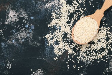 Gri arka planda tahta kaşıkta susam tohumları