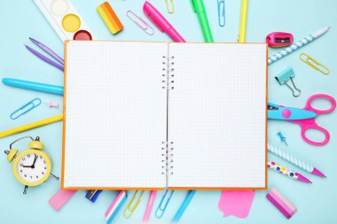 Mavi arkaplandaki metin için boş not defteri içeren okul malzemeleri