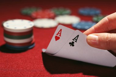 Poker fişleri ve kırmızı masada kadın eli kartları.