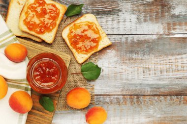 Kayısı, kasede reçel ve ahşap zeminde ekmek tostu.