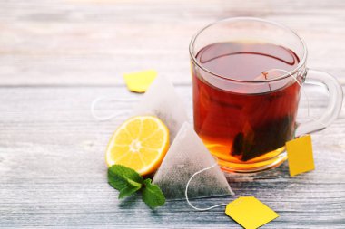 Çay poşetleri, nane yaprakları ve ahşap masada limon.