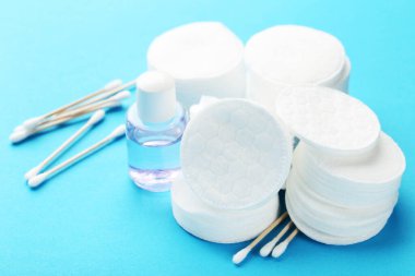 Yumuşak pamuklu çubuklu ve mavi arka planda kozmetik şişeli.