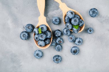 Gri arka planda ahşap kaşıklarda yabanmersini