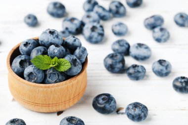 Tahta arka planda yeşil yapraklı tatlı yaban mersinleri.