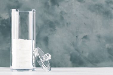 Gri arkaplanda plastik kavanozda pamuk pedler