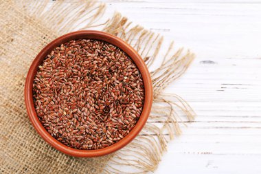 Kahverengi kasedeki keten tohumları beyaz ahşap arka planda