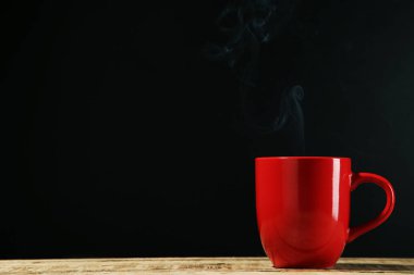 Siyah arka planda buharlı bir bardak içki.