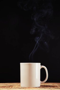 Siyah arka planda buharlı bir bardak içki.