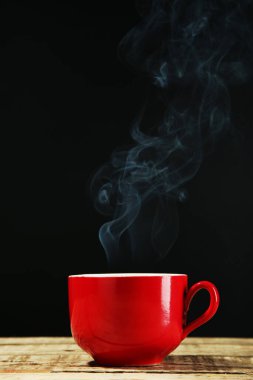 Siyah arka planda buharlı bir bardak içki.