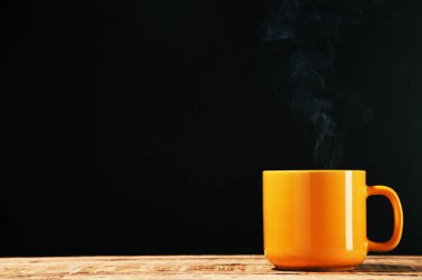 Siyah arka planda buharlı bir bardak içki.