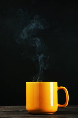 Siyah arka planda buharlı bir bardak içki.