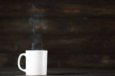 Kahverengi ahşap masada buharlı bir bardak içki.