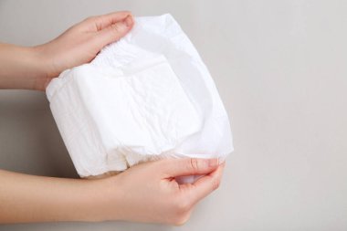Gri arka planda kadın eli olan bebek bezi.