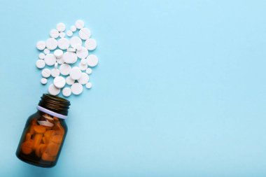 Mavi arka planda ilaç hapları ve şişe