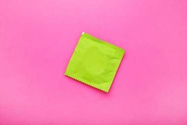 Pembe arka planda yeşil prezervatif