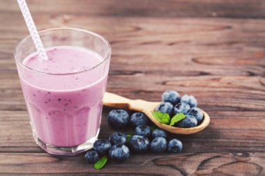 Böğürtlenli yabanmersini kokteyli ve ahşap arka planda yeşil yapraklar.