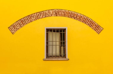 Sarı duvarda ızgara olan pencere