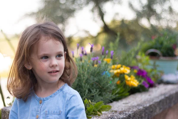 Malá Krásná Dívka Stojí Džínové Modré Šaty Pozadí Jasných Květin — Stock fotografie