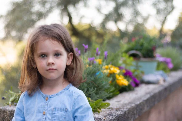 Malá Krásná Školačka Stojí Džínových Modrých Šatech Pozadí Květin — Stock fotografie