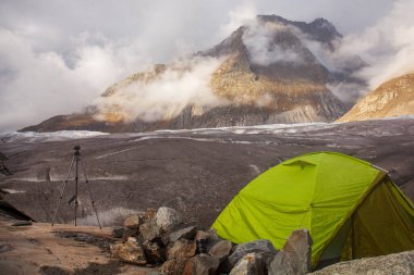 İsviçre dağlarında, Aletsch Buzulu ve Olmenhorn Dağı 'na bakan bir çadır ve tripod macera ve sükunet manzarası yaratıyor..