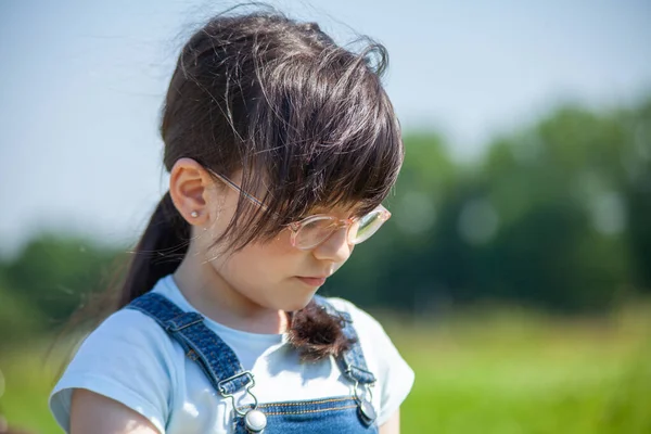 一个戴着太阳镜和蓝色工作服的可爱小女孩的画像 — 图库照片
