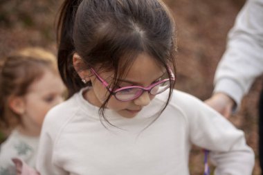 Gözlüklü küçük kız ve parkta beyaz tişört.