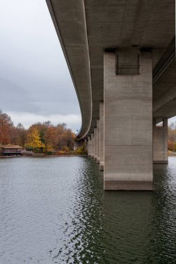 Bulutlu bir sonbahar gününde nehir üzerindeki beton köprü.