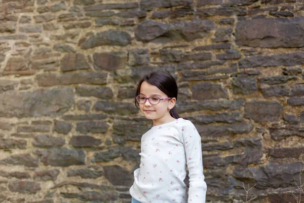 Gadis Kecil Yang Lucu Memakai Kacamata Berdiri Depan Dinding Batu — Stok Foto