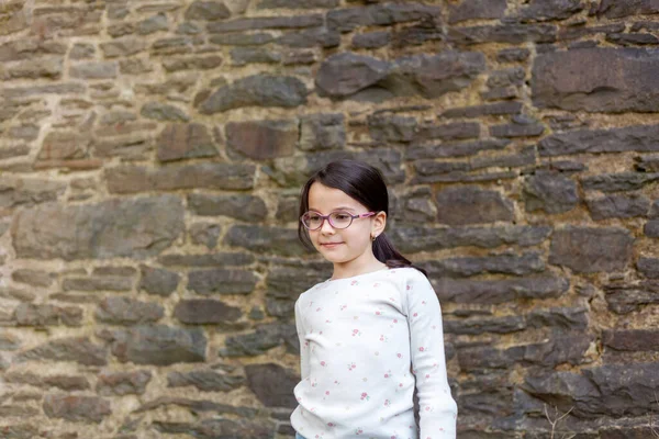 Taş Bir Duvara Yaslanmış Gözlüklü Küçük Bir Kızın Portresi — Stok fotoğraf