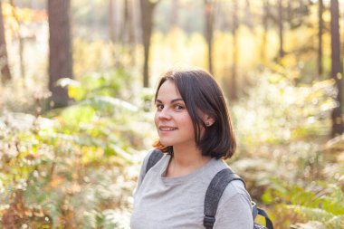 Sırt çantalı ve kameraya bakan güzel bir genç kadının portresi.