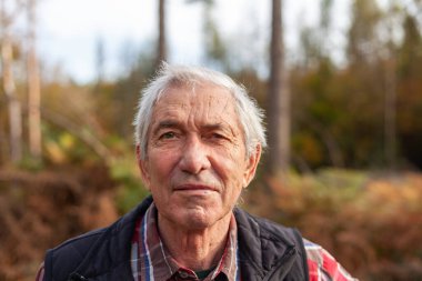 Sonbaharda orman yolunda duran yaşlı bir adamın portresi.