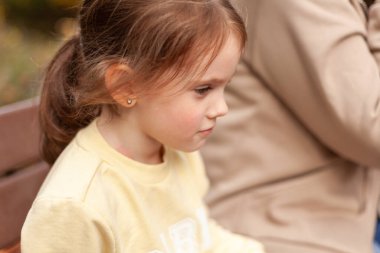 Parktaki bankta oturan sevimli küçük bir kızın portresi.