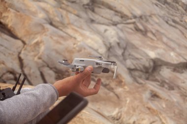 Erkek elinin uzaktan kumandayla kayanın üzerinde uzaktan kumandayla ve dronla