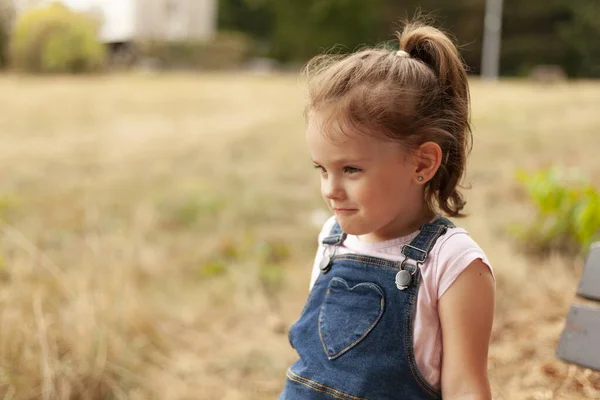 Egy Gyönyörű Szőke Lány Farokkal Egy Padon Parkban Farmer Overálban — Stock Fotó