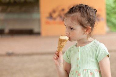 Elbiseli güzel sarışın kız açık havada dondurma yiyor.
