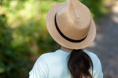 Parkta duran hasır şapkalı bir kızın arka plan görüntüsü.