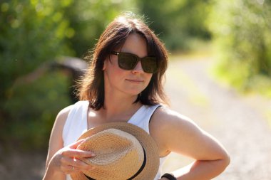 Köyde yürürken şapka ve güneş gözlüğü takan güzel genç bir kadın.