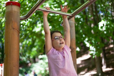 Parktaki barfiks çubuğunda asılı duran küçük kız..