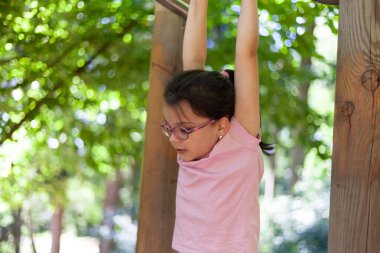 Parktaki barfiks çubuğunda asılı duran küçük kız..