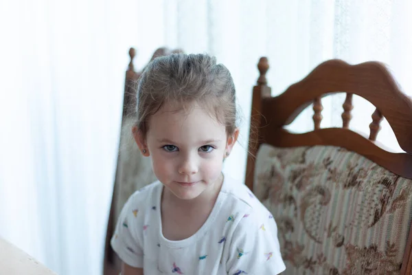 一个可爱的小女孩坐在家里椅子上的画像 — 图库照片