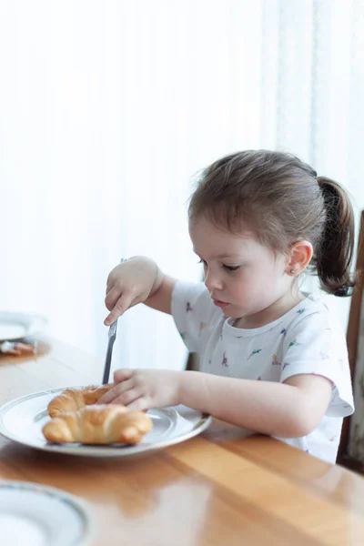 Aranyos Kislány Croissant Eszik Otthon Konyhában — Stock Fotó