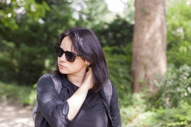 Güneş gözlüklü güzel bir kız ve parkta siyah bir gömlek.